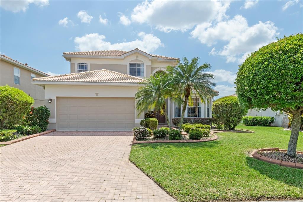 A two-story suburban house with a tan exterior, tile roof, and a paved driveway — 6918 74TH STREET CIRCLE E, BRADENTON, FL