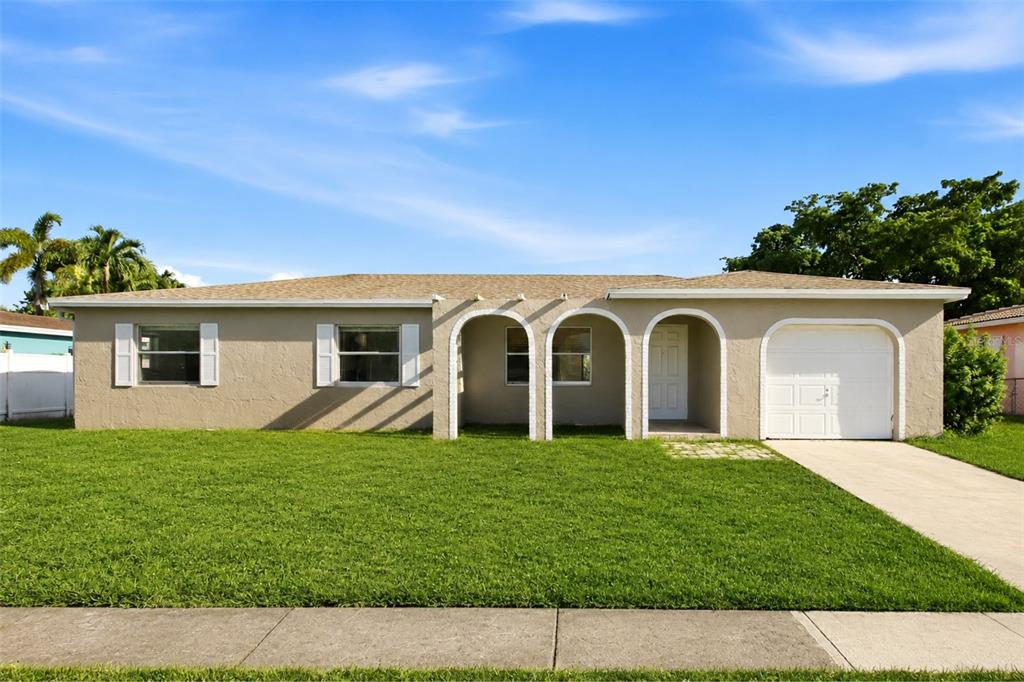 A single-story house with a tan stucco exterior, arched entryway, and an attached garage — 10894 GRANITE STREET, BOCA RATON, FL