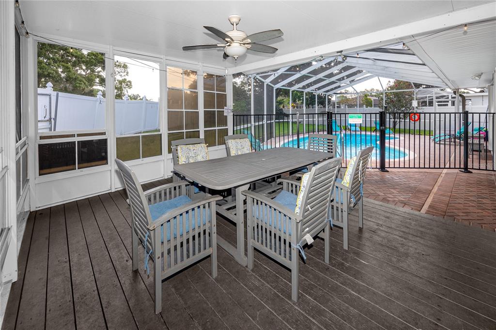 A screened-in patio with a dining set, ceiling fan, and a view of a swimming pool — 12291 MONARCH CIRCLE, SEMINOLE, FL