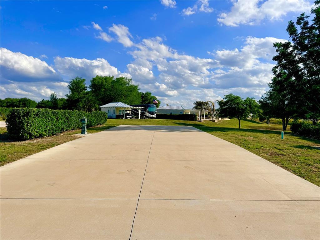 A large concrete driveway leads toward a house with a parked RV under a carport — 4982 SE 92ND BOULEVARD, WEBSTER, FL