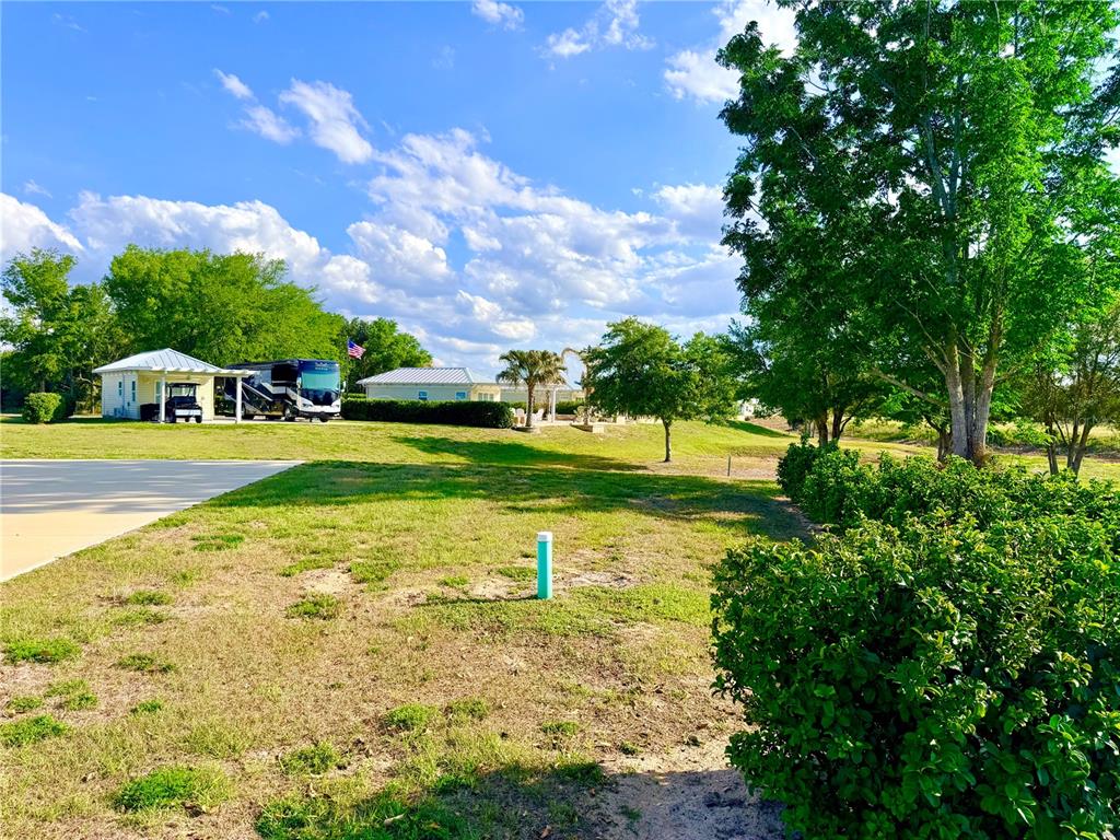 A grassy yard features a small white building, a parked RV, and mature trees — 4982 SE 92ND BOULEVARD, WEBSTER, FL