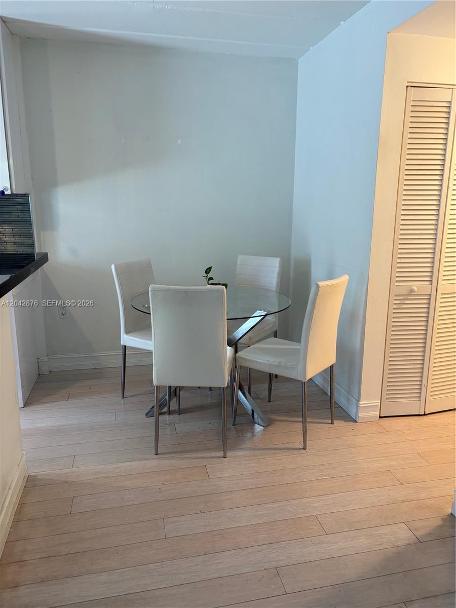 A dining area features a glass-topped table with four white chairs on light wood flooring — 1545 Euclid Ave # 2F, Miami Beach FL 33139, MIAMI BEACH, FL