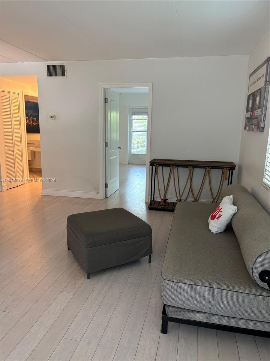 A living room features light wood flooring, a gray sofa, an ottoman, and a console table — 1545 Euclid Ave # 2F, Miami Beach FL 33139, MIAMI BEACH, FL