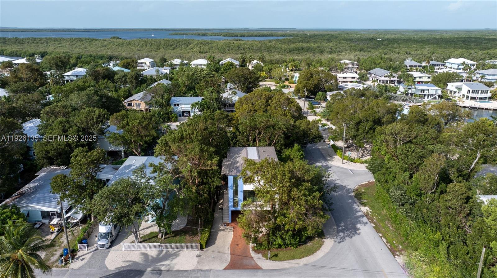 An aerial view shows a blue house surrounded by trees near a coastal waterway — 669 Colson Dr, Key Largo FL 33037, KEY LARGO, FL