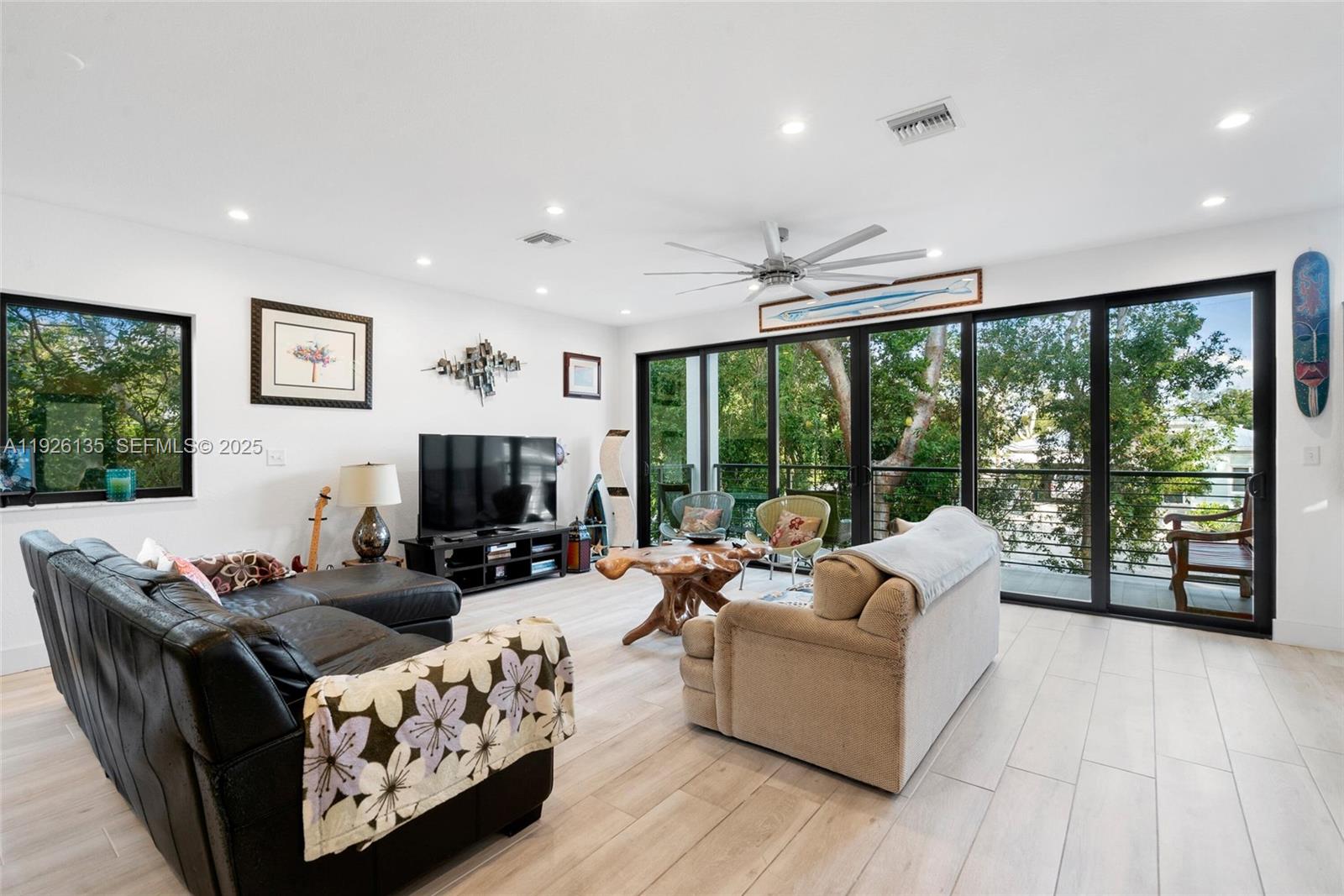 A living room features light wood-look tile floors, a black leather sectional, and sliding glass doors — 669 Colson Dr, Key Largo FL 33037, KEY LARGO, FL