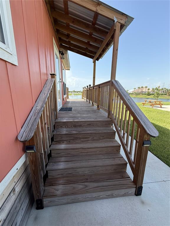 A wooden staircase leads to a covered porch on the side of a coral-colored building — 235 CLUB LANE UNIT 235, PUNTA GORDA, FL