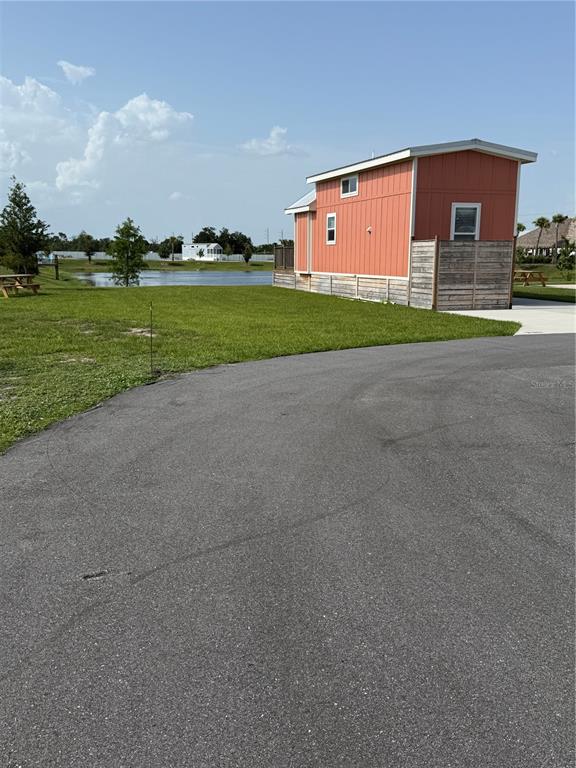 A small orange cabin sits on a grassy lot next to a pond — 235 CLUB LANE UNIT 235, PUNTA GORDA, FL