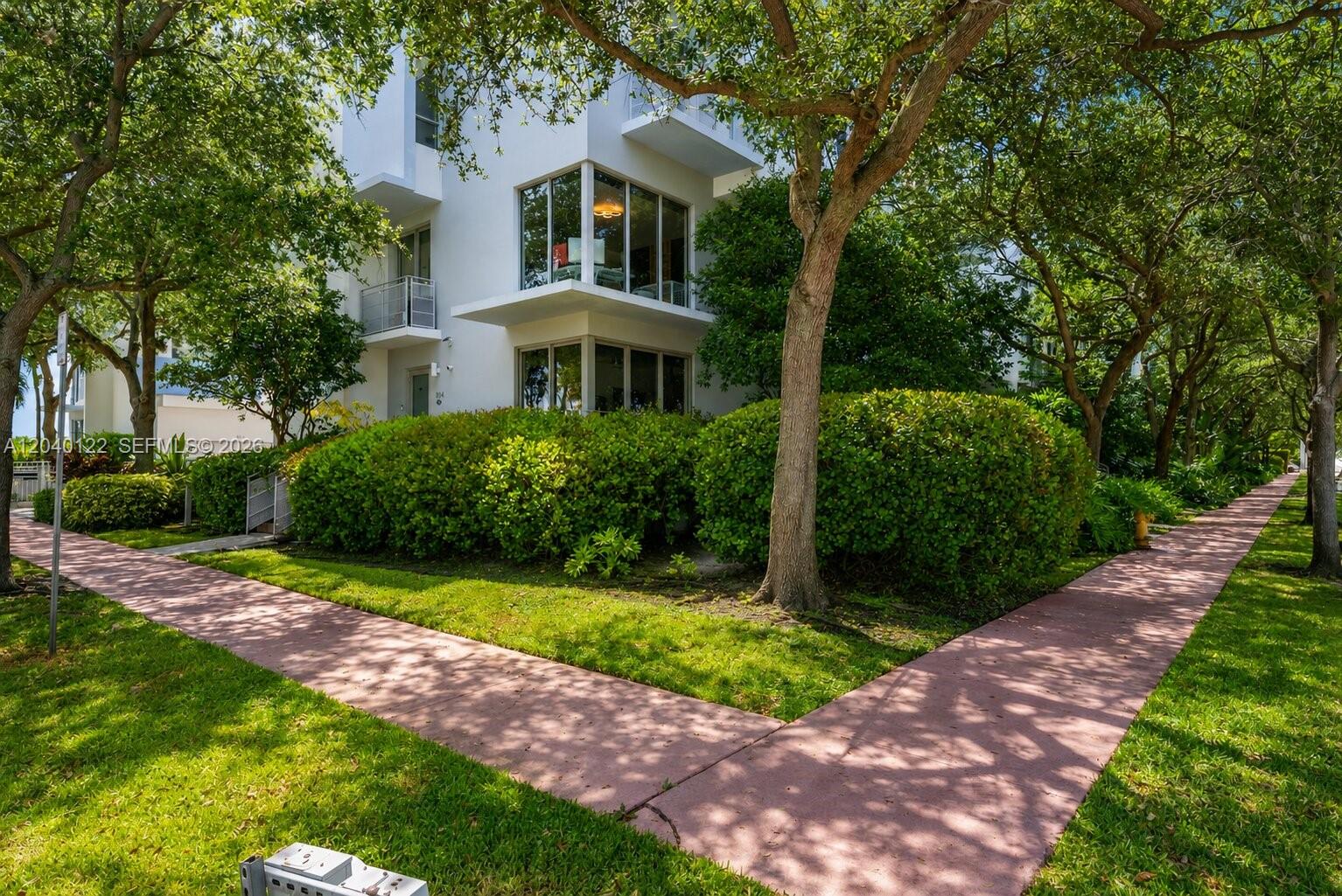 A white multi-story building is surrounded by green trees and a pink paved walkway — 193 N Shore Dr # 6, Miami Beach FL 33141, MIAMI BEACH, FL