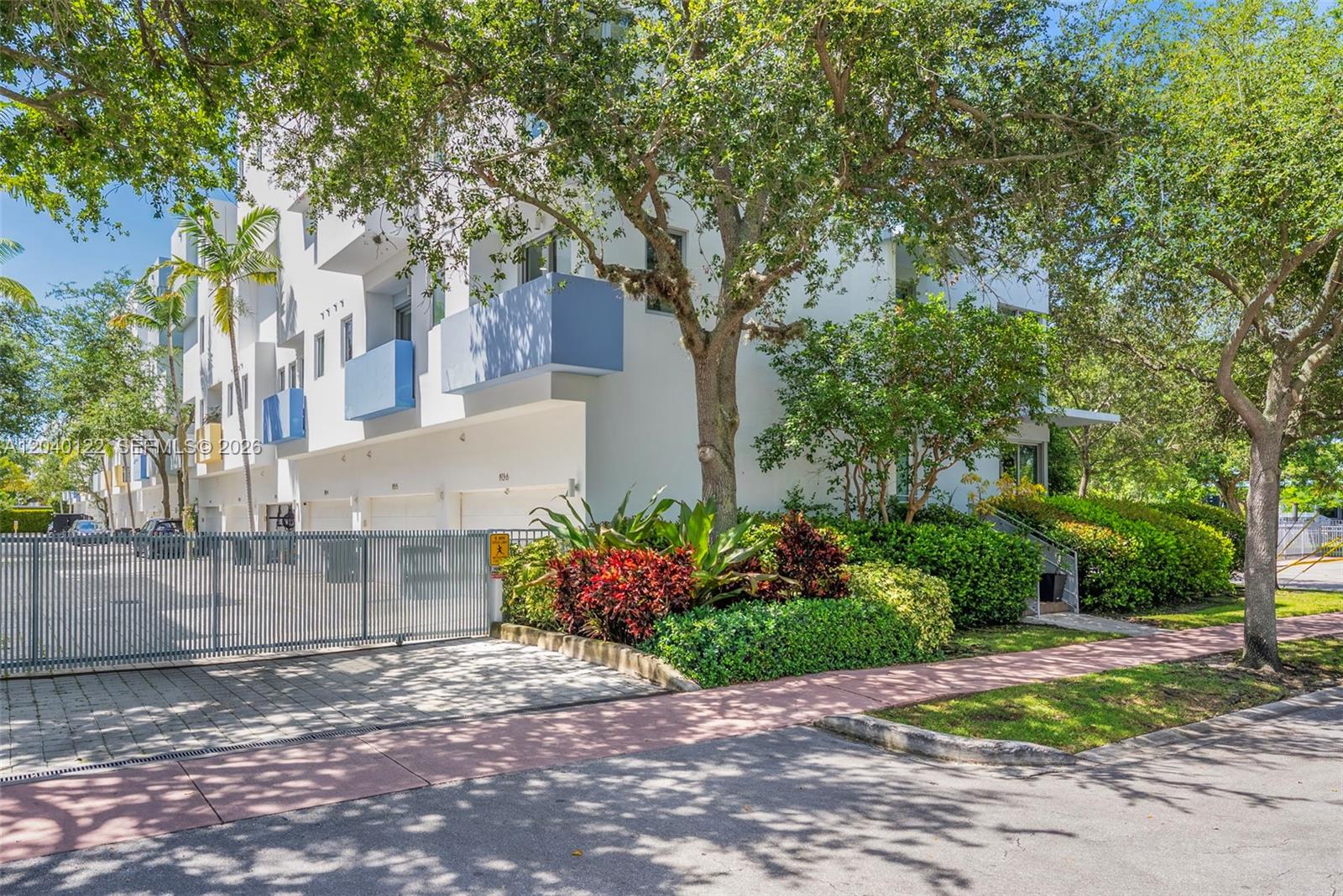 A multi-story white residential building with blue balconies, a gated entrance, and lush landscaping — 193 N Shore Dr # 6, Miami Beach FL 33141, MIAMI BEACH, FL