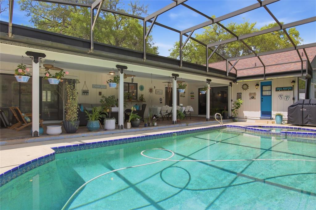 A screened-in swimming pool sits in front of a covered patio with outdoor seating — 128 W GREENTREE LANE, LAKE MARY, FL