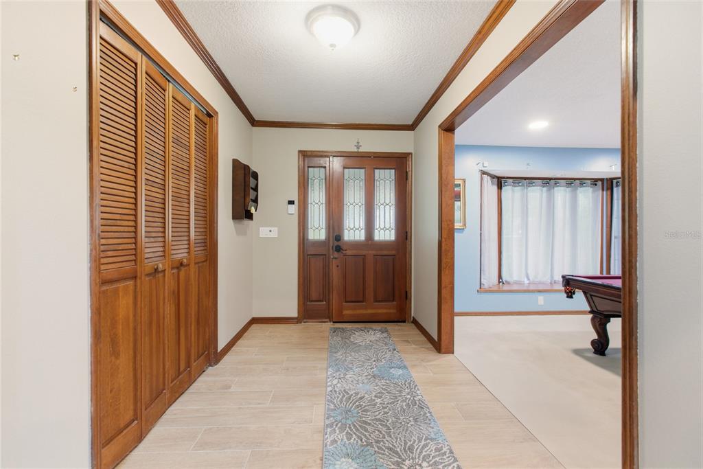 An entryway features a wooden front door, louvered closet doors, tile flooring, and a runner rug — 128 W GREENTREE LANE, LAKE MARY, FL
