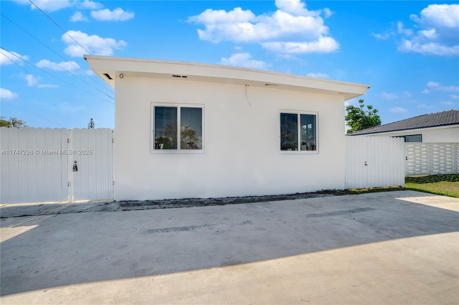A white, flat-roofed detached structure stands behind a white fence on a concrete driveway — 10272 SW 178th St # 1, Miami FL 33157, MIAMI, FL