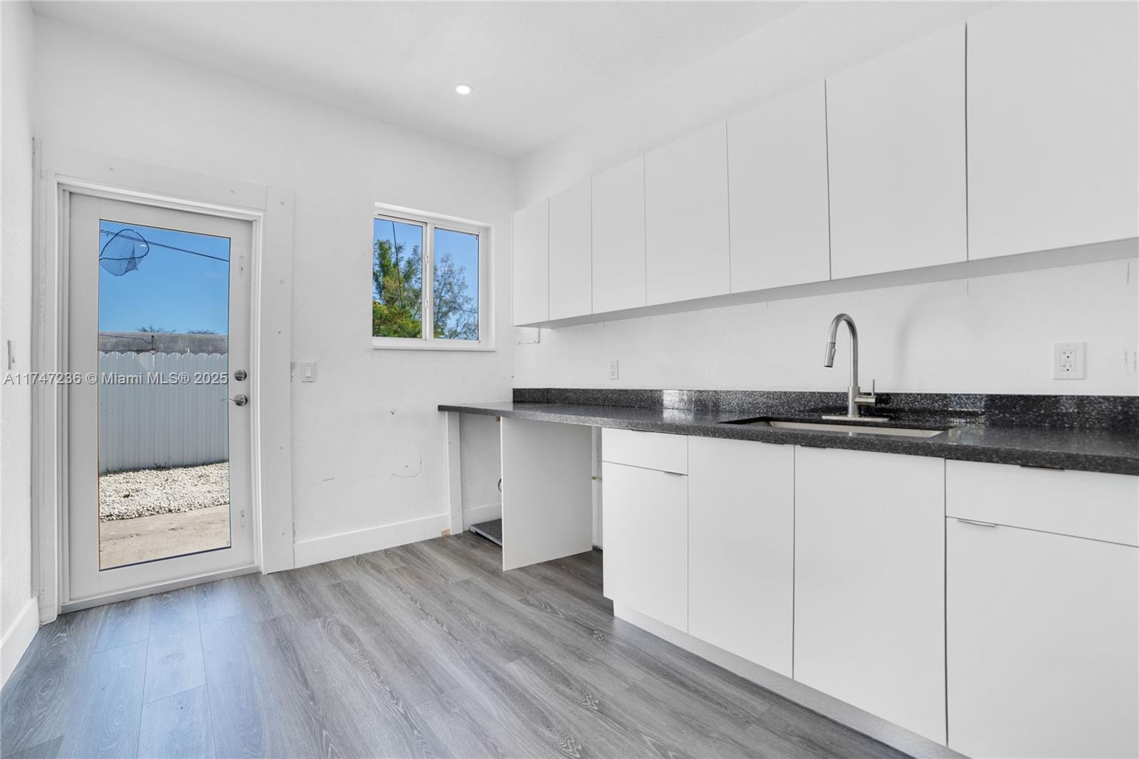 A kitchen features white cabinets, a dark speckled countertop, and a glass-paned exterior door — 10272 SW 178th St # 1, Miami FL 33157, MIAMI, FL