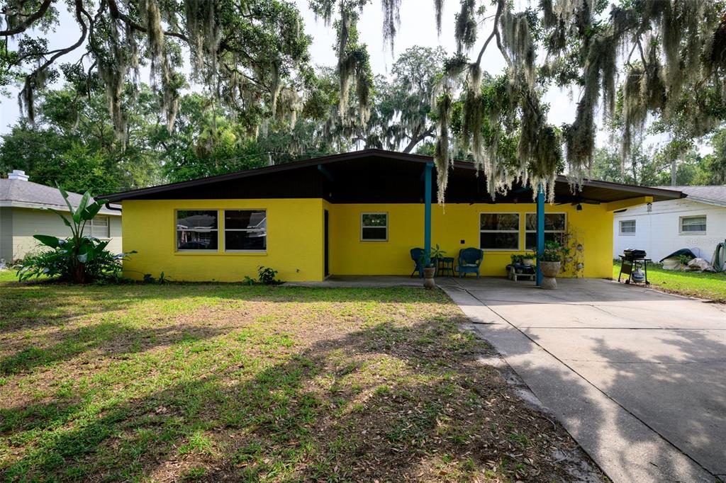 A bright yellow single-story house features a covered front porch and a concrete driveway — 1003 CHEROKEE RANCH ROAD, HOLLY HILL, FL