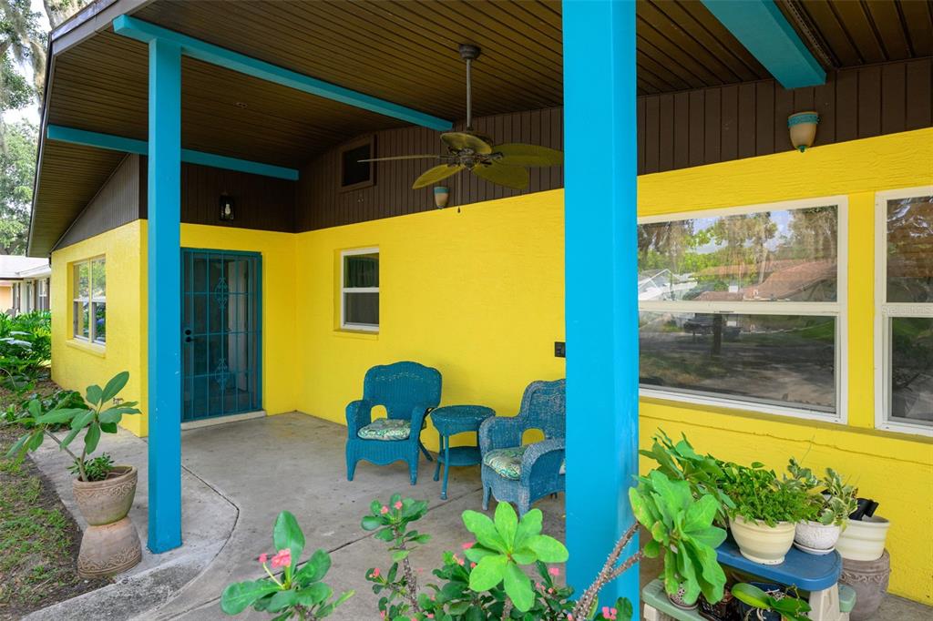 A covered patio with yellow walls, blue support beams, and blue wicker furniture — 1003 CHEROKEE RANCH ROAD, HOLLY HILL, FL