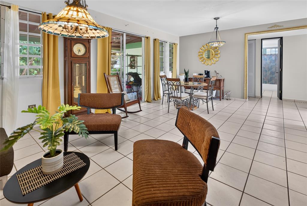 A living and dining area features tiled floors, a grandfather clock, and a glass sliding door — B-21 MANSIONES DE CABO ROJO, CABO ROJO, PR