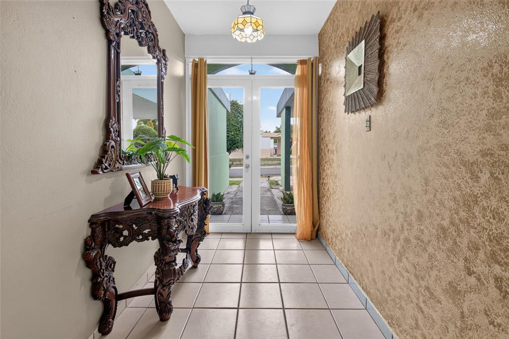 An entryway features a tiled floor, an ornate wooden console table, and a glass-paned door — B-21 MANSIONES DE CABO ROJO, CABO ROJO, PR