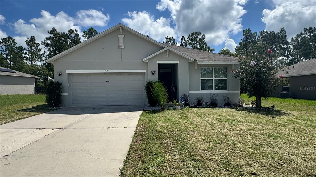 A single-story suburban house with a two-car garage and a concrete driveway — 259 HICKORY COURSE RADIAL, OCALA, FL