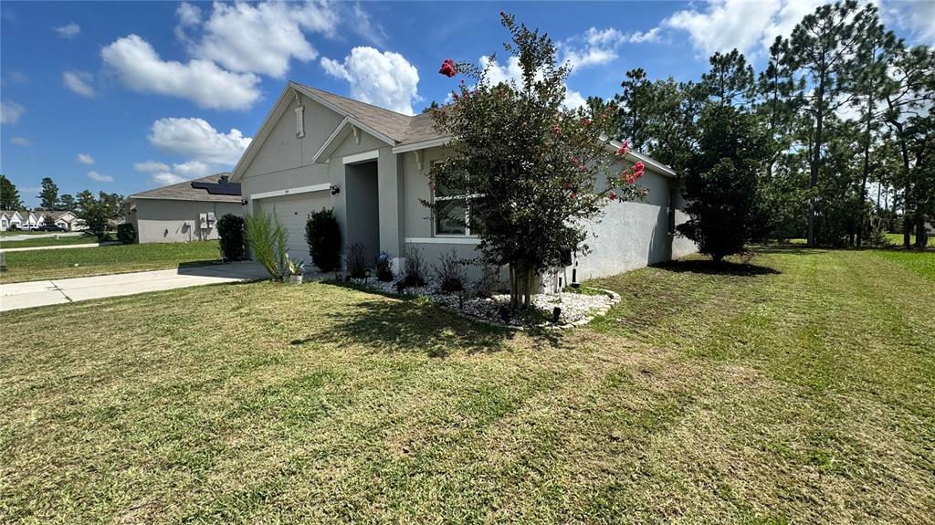 A single-story house with a gray stucco exterior, a concrete driveway, and a landscaped yard — 259 HICKORY COURSE RADIAL, OCALA, FL