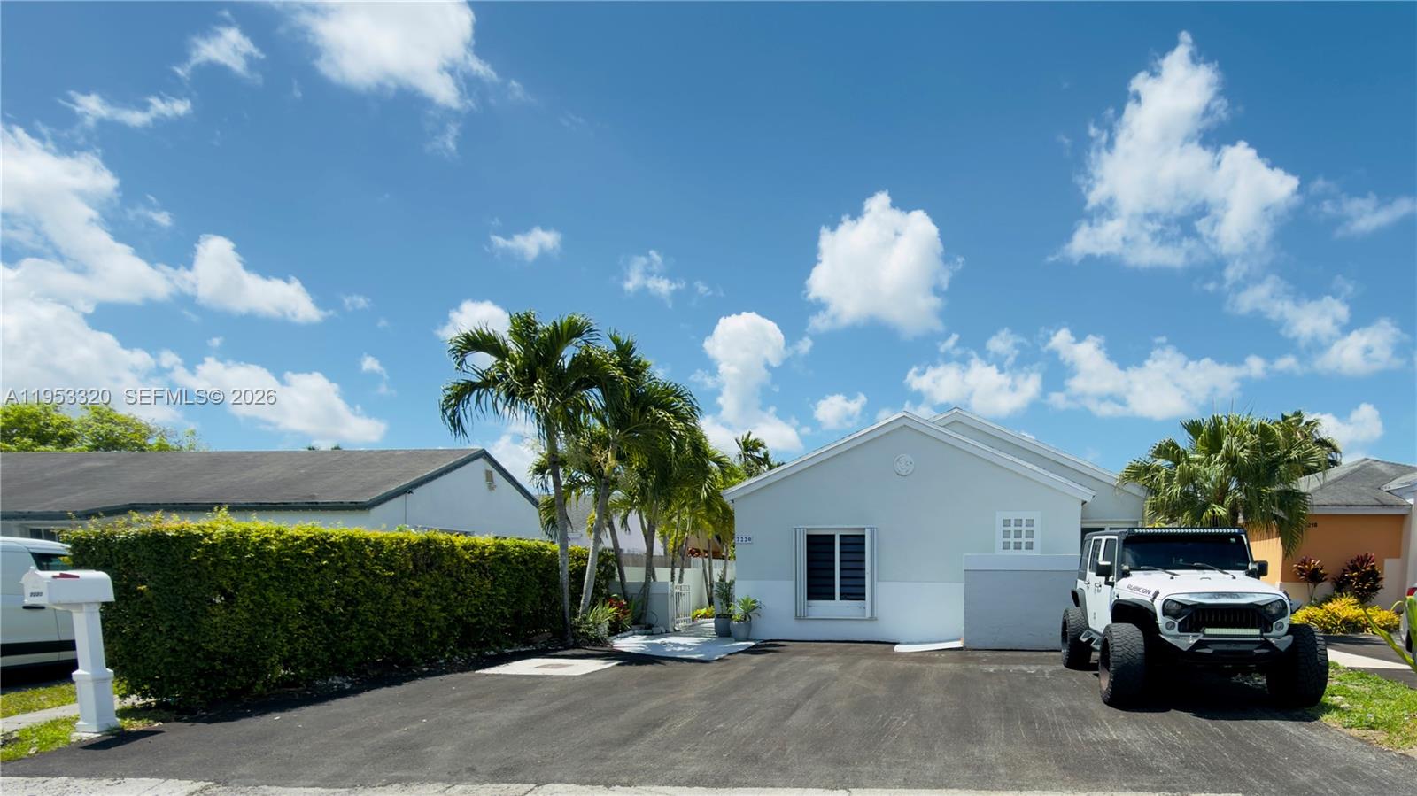 A light-colored single-story house features a paved driveway, a white Jeep, and palm trees — 7220 SW 149th Ct, Miami FL 33193, MIAMI, FL