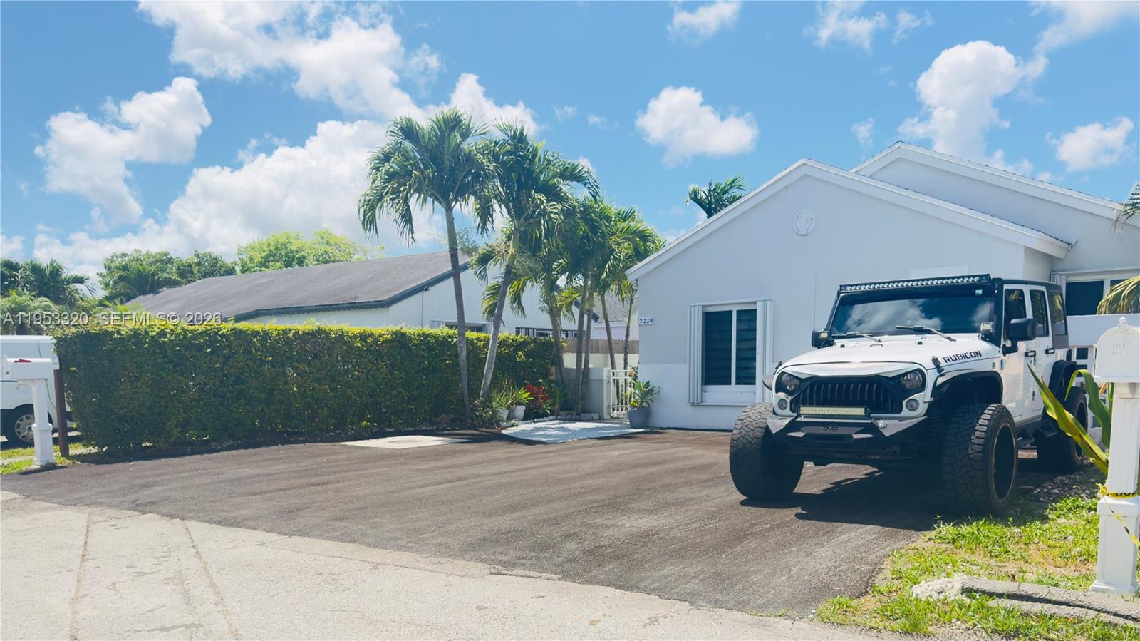 A white Jeep Rubicon is parked on a paved driveway in front of a house — 7220 SW 149th Ct, Miami FL 33193, MIAMI, FL