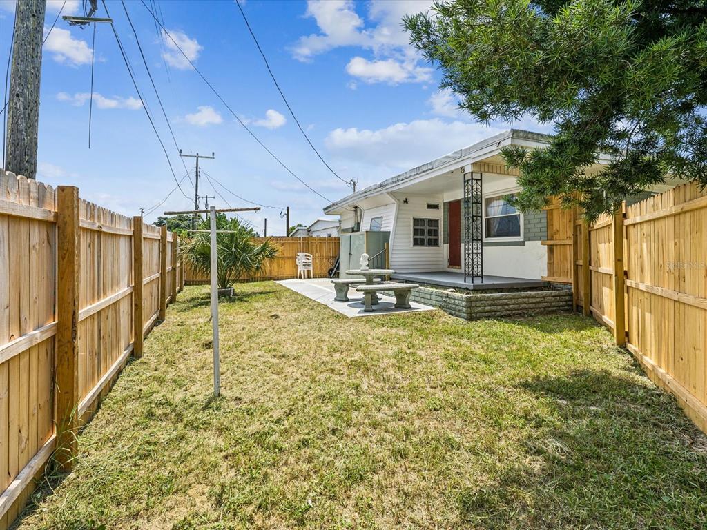 A fenced backyard features a small concrete patio with a stone table and bench set — 1940 SHADY COVE DRIVE, HOLIDAY, FL