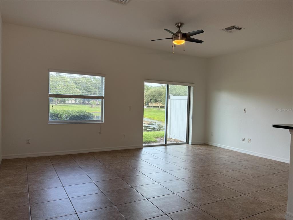 An empty living room features tile flooring, a ceiling fan, and sliding glass doors — 12243 CITRUSWOOD DRIVE, ORLANDO, FL
