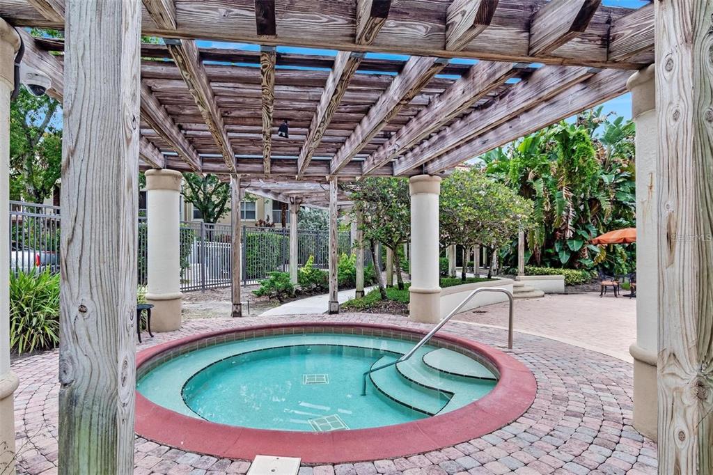 A circular hot tub sits under a wooden pergola on a brick patio — 829 CAMARGO WAY UNIT 209, ALTAMONTE SPRINGS, FL