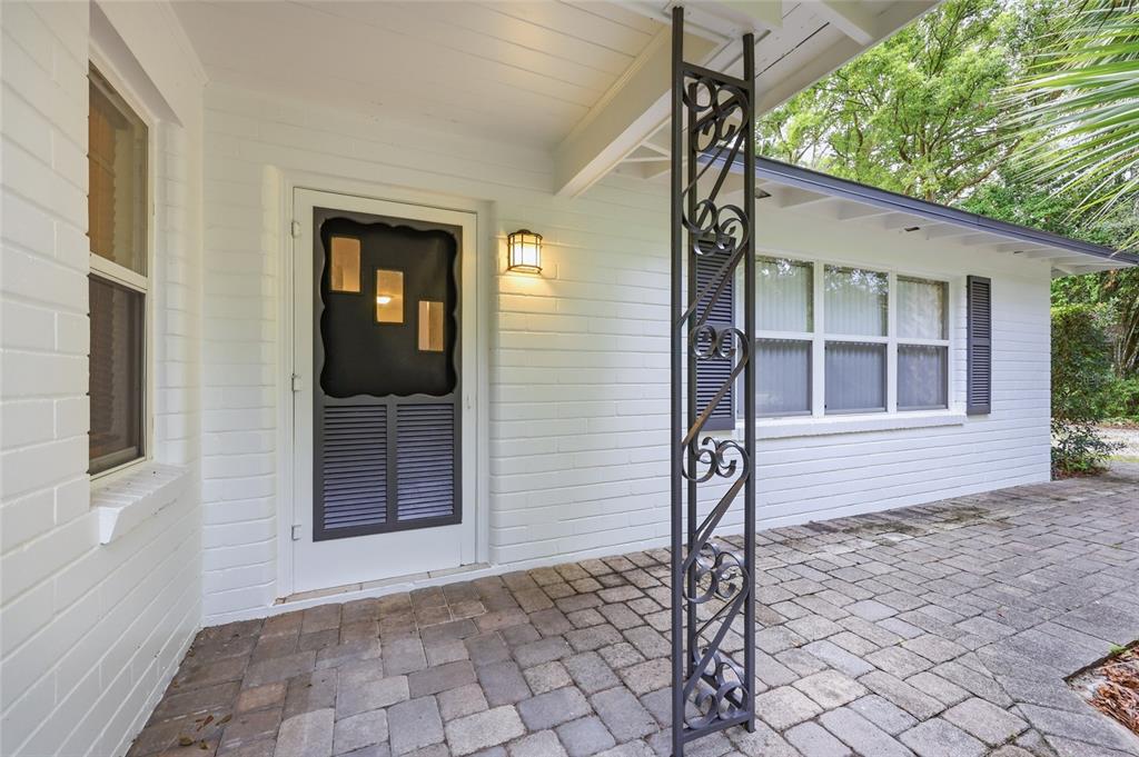 A white brick house exterior features a front porch with a decorative metal support column — 1503 NW 17TH STREET, GAINESVILLE, FL