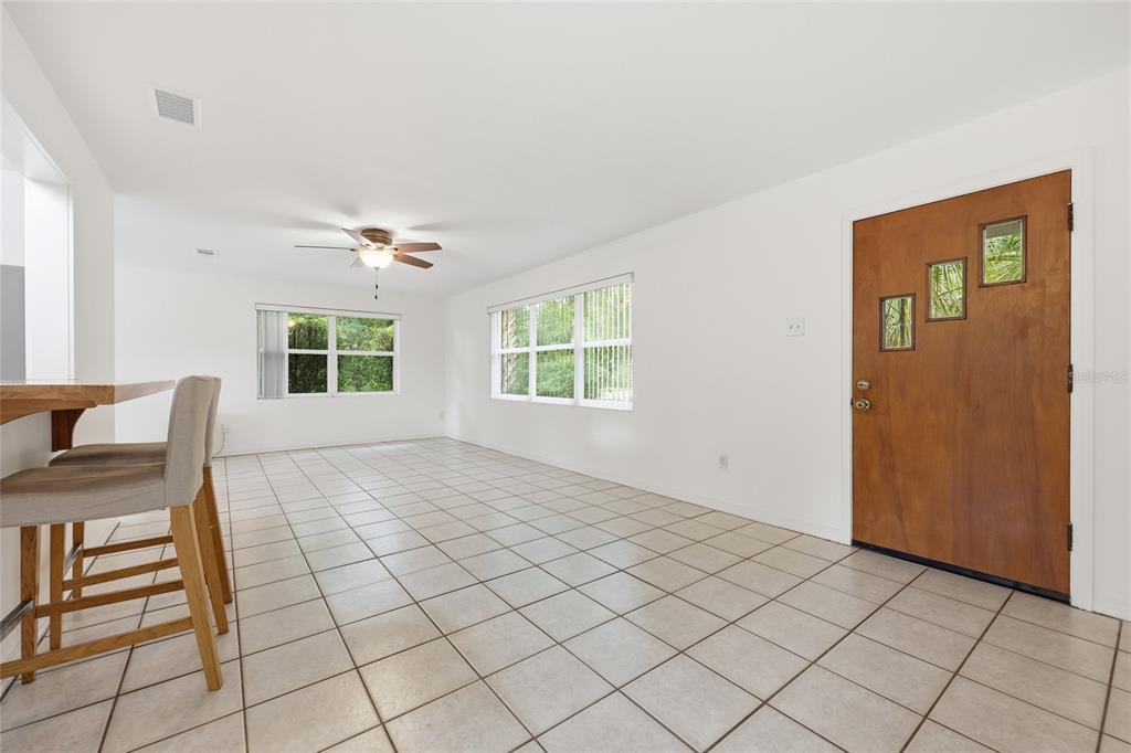 A bright, tiled living area features a wooden front door, ceiling fan, and breakfast bar — 1503 NW 17TH STREET, GAINESVILLE, FL