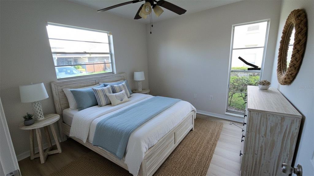 A bedroom features a bed with blue bedding, two side tables, and a large round mirror — 4849 ONYX LANE UNIT 101, NEW PORT RICHEY, FL