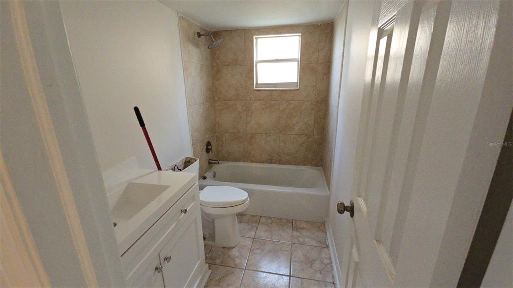 A bathroom features a white vanity, a toilet, and a bathtub with tiled walls — 4849 ONYX LANE UNIT 101, NEW PORT RICHEY, FL
