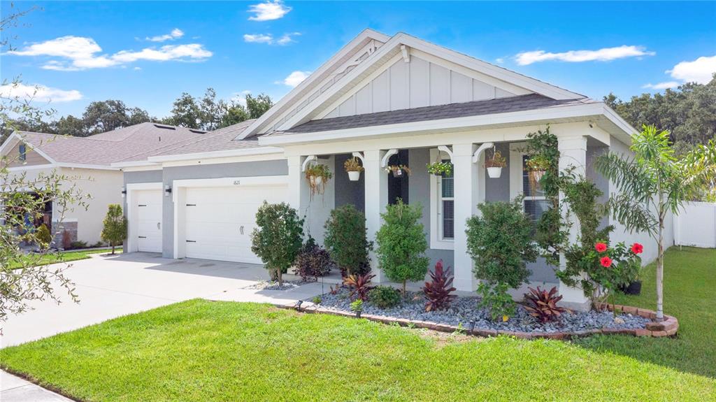 A single-story house with a gray exterior, a two-car garage, and a covered front porch — 1621 PARK SIDE AVENUE, KISSIMMEE, FL