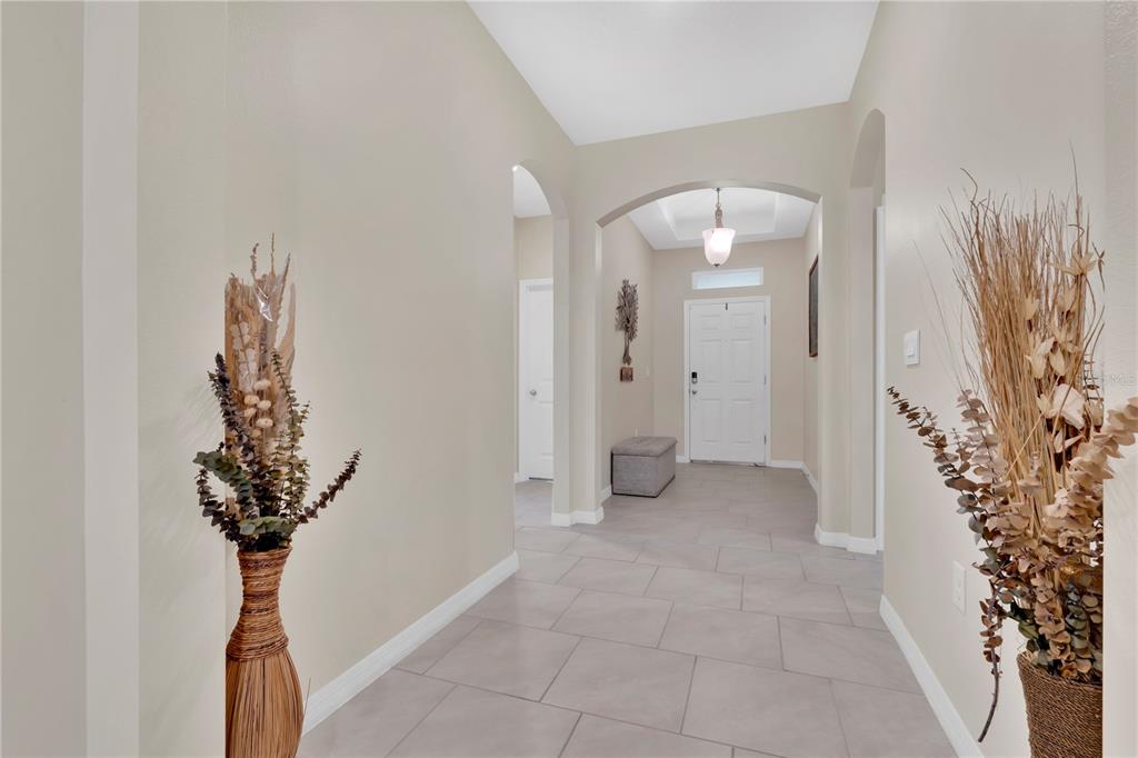 A tiled entryway features arched doorways, neutral walls, and two large decorative floor vases — 1621 PARK SIDE AVENUE, KISSIMMEE, FL