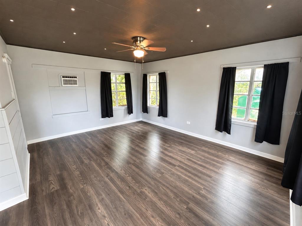 A room with dark wood flooring, a dark ceiling with recessed lighting, and black curtains — 8010 SE US HIGHWAY 301 UNIT 4B, HAWTHORNE, FL