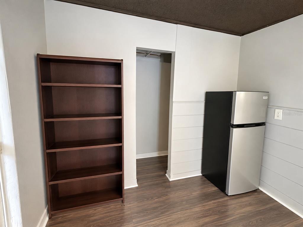 A room features a dark wood bookshelf, a stainless steel refrigerator, and a walk-in closet — 8010 SE US HIGHWAY 301 UNIT 4B, HAWTHORNE, FL