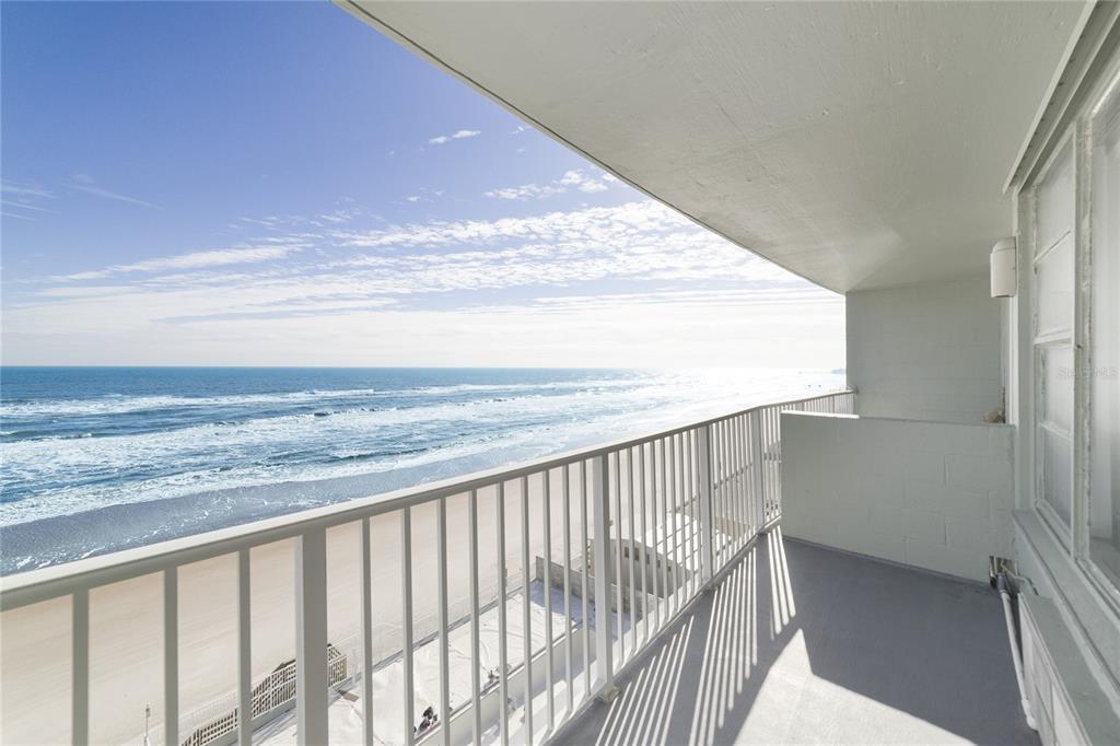A balcony with a white metal railing overlooks a sandy beach and the ocean — 800 N ATLANTIC AVENUE UNIT 705, DAYTONA BEACH, FL