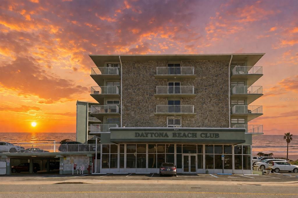An exterior view of the Daytona Beach Club building at sunset with oceanfront balconies — 800 N ATLANTIC AVENUE UNIT 705, DAYTONA BEACH, FL