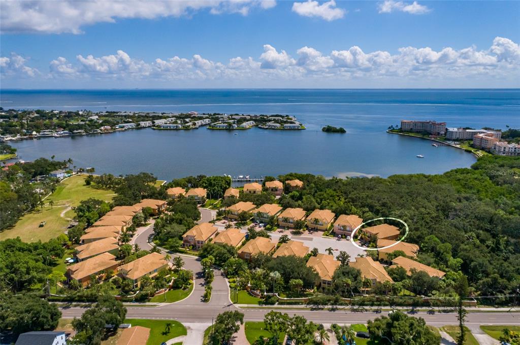 An aerial view shows a residential community with tan-roofed buildings near a large bay — 190 BANYAN BAY DRIVE, ST PETERSBURG, FL