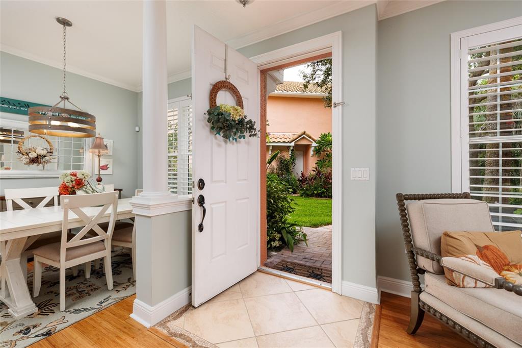 An open front door reveals a courtyard view from an entryway with tile and wood flooring — 190 BANYAN BAY DRIVE, ST PETERSBURG, FL