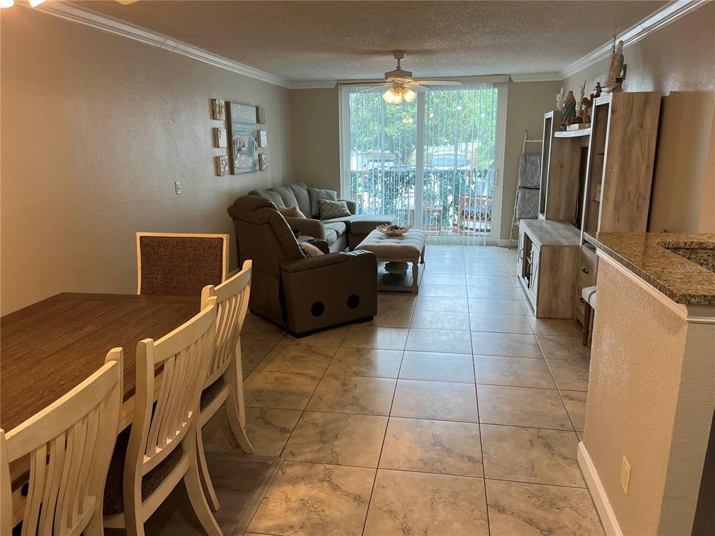 A dining area and living room with tile flooring, a ceiling fan, and sliding glass doors — 2700 COCONUT BAY LN LANE UNIT 4111, SARASOTA, FL