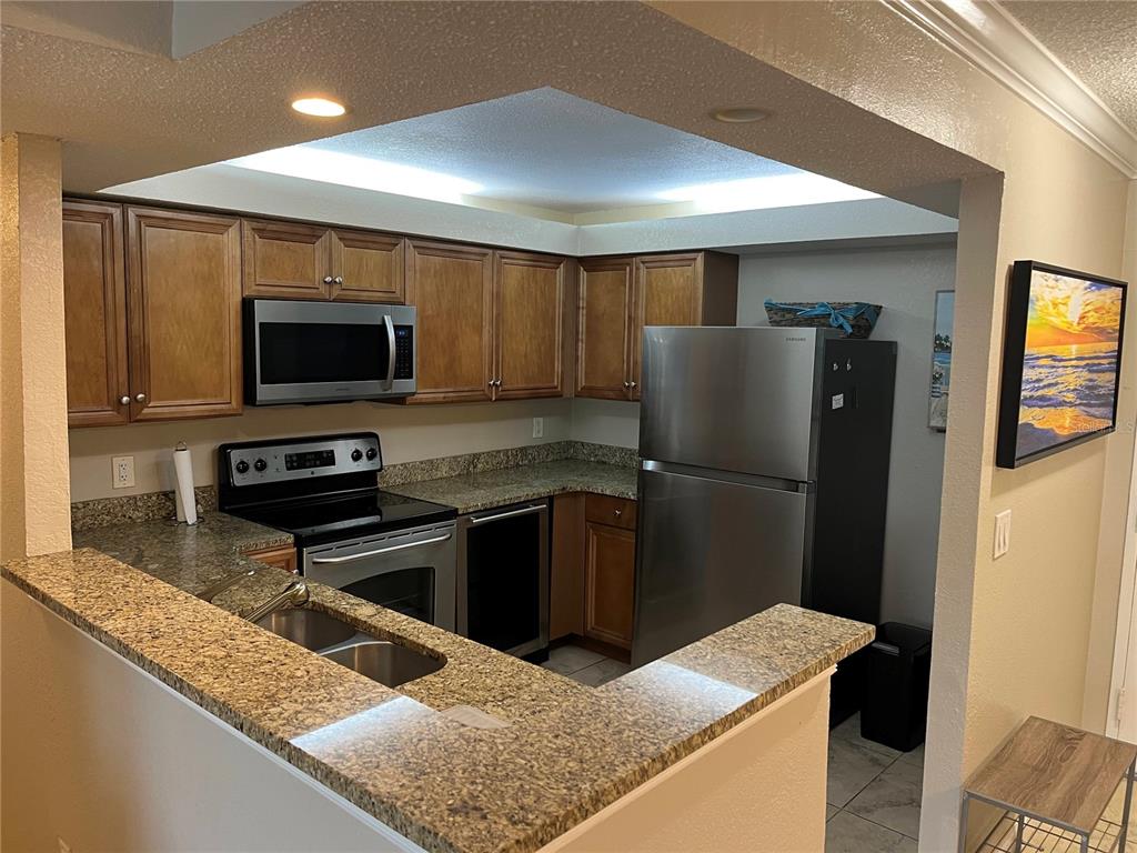 A kitchen features wood cabinets, granite countertops, stainless steel appliances, and a breakfast bar — 2700 COCONUT BAY LN LANE UNIT 4111, SARASOTA, FL