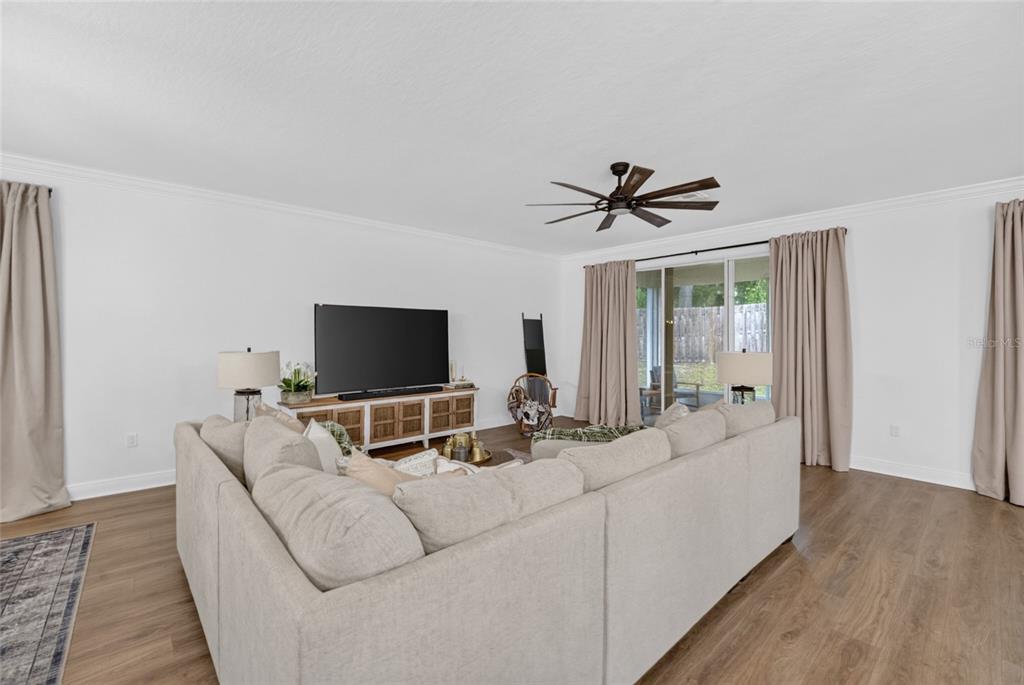 A living room features a large sectional sofa, a television console, and sliding glass doors — 12377 NW 157TH TERRACE, ALACHUA, FL