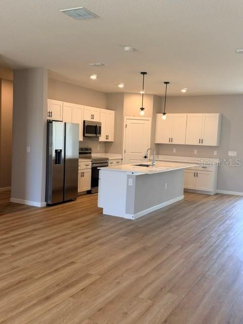 A modern kitchen features white cabinets, stainless steel appliances, and a central island — 10866 SW 41 ST AVENUE, OCALA, FL