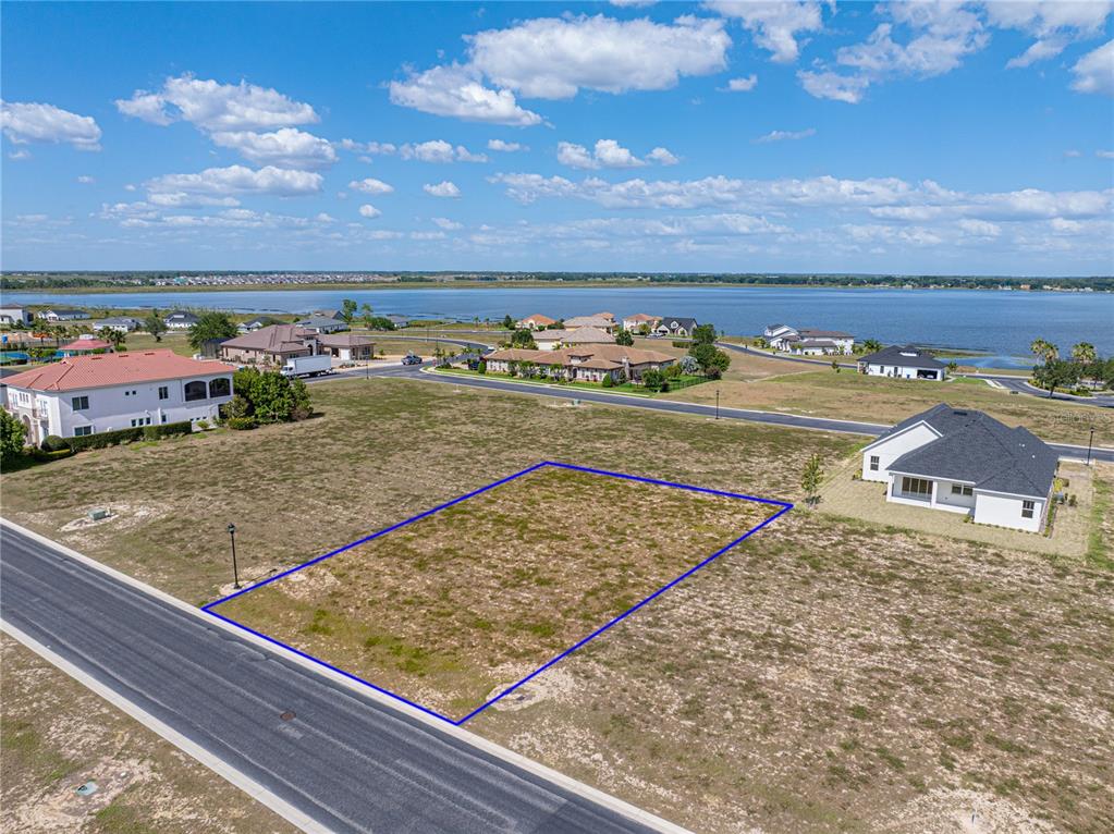 An aerial view shows a vacant rectangular lot outlined in blue next to a suburban house — 158 BLAZING STAR AVENUE, LAKE ALFRED, FL