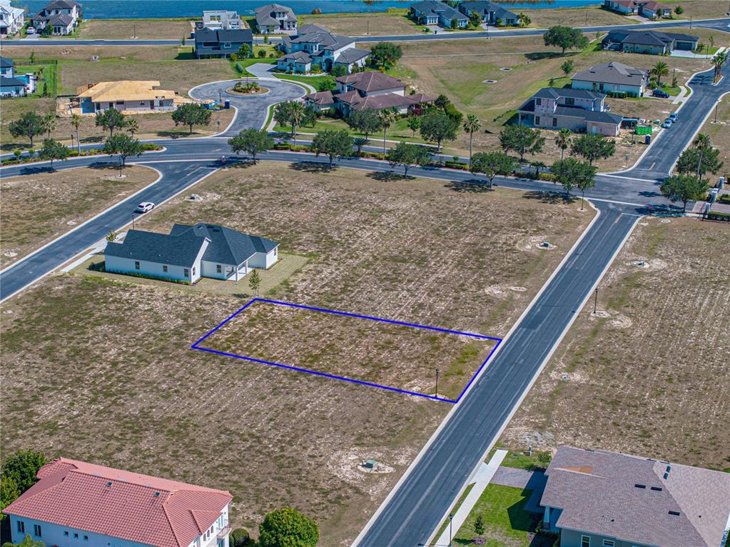 An aerial view shows a vacant rectangular residential lot outlined in blue within a neighborhood — 158 BLAZING STAR AVENUE, LAKE ALFRED, FL
