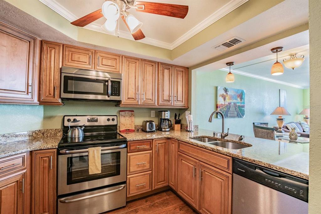 A kitchen with wood cabinets, granite countertops, stainless steel appliances, and an open floor plan — 6295 BAHIA DEL MAR CIRCLE UNIT 401, ST PETERSBURG, FL