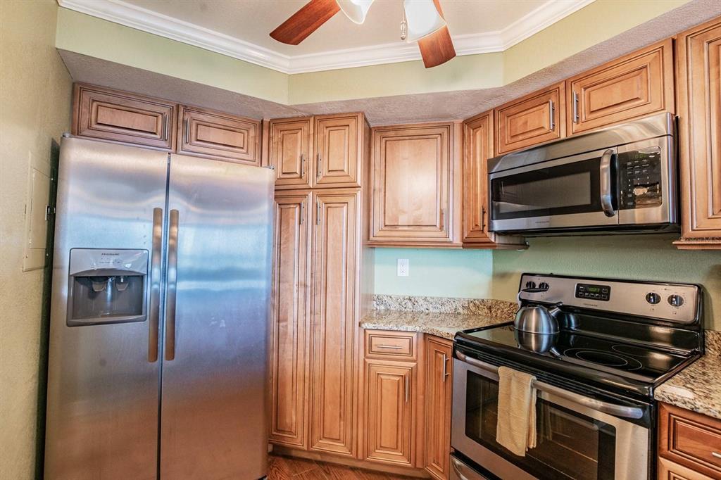 A kitchen features stainless steel appliances, wood cabinets, and granite countertops — 6295 BAHIA DEL MAR CIRCLE UNIT 401, ST PETERSBURG, FL