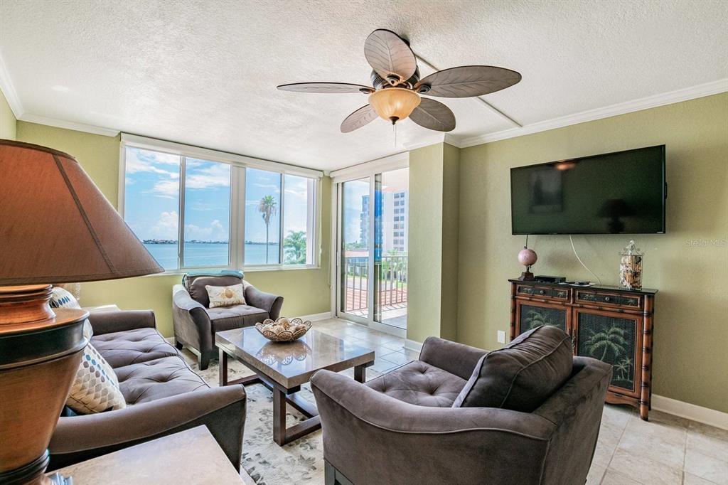 A living room features a ceiling fan, dark furniture, and a view of the water — 6295 BAHIA DEL MAR CIRCLE UNIT 401, ST PETERSBURG, FL