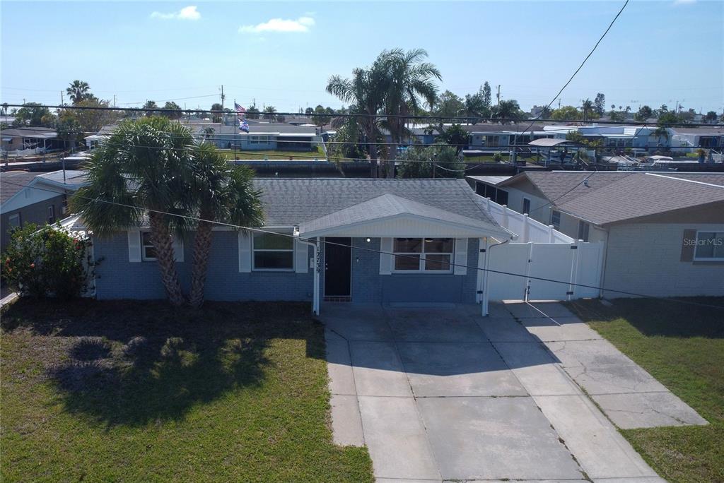 A single-story gray brick house with a concrete driveway and a palm tree out front — 12739 1ST ISLE, HUDSON, FL